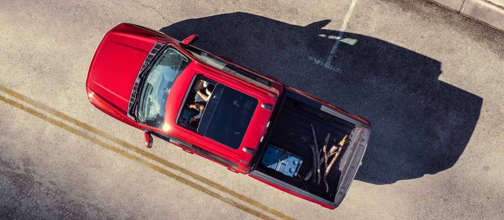 An aerial view of two people in a 2025 Ford F-150® Lightning® featuring the sunroof and cargo in the truck bed