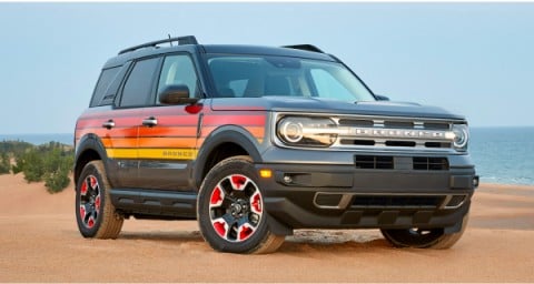 Picture of the new 2024 Bronco® Sport Free Wheeling™ model, with sunset-colored, striped side panels,  parked in the sand.
