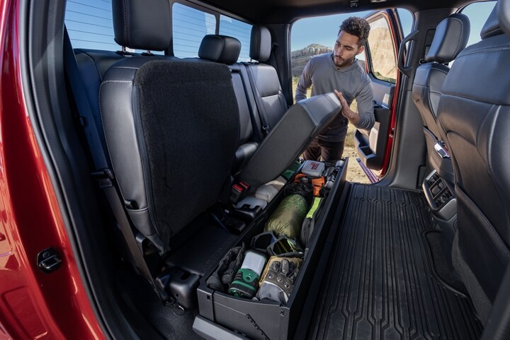 Man lifting the lockable under-seat storage showing the storage bin with items inside