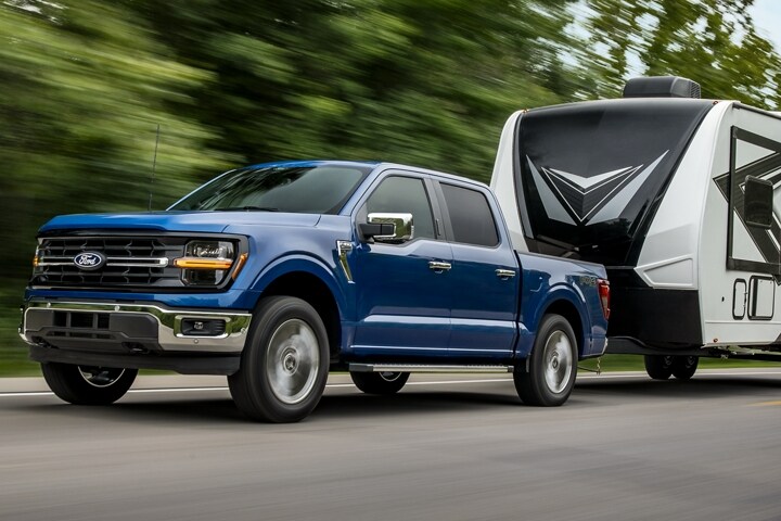 2024 Ford F-150® XLT pickup in Atlas Blue pulling a camper